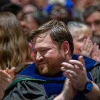Faculty members and guests applaud and smile in the audience